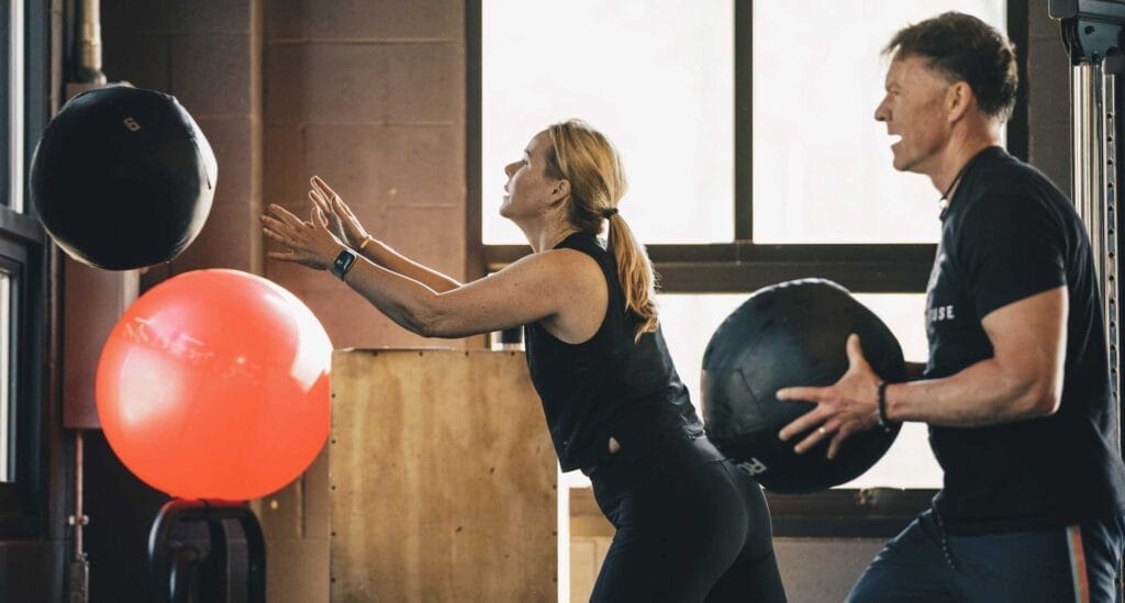 Man and woman throwing a wall ball on small group personal training